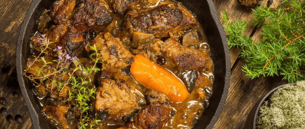 Cast iron pot of venison beef stew with carrots for furry friends