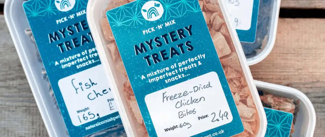 Natural Cornish Pet mystery treats box with blue and white container holding freeze-dried chicken bits