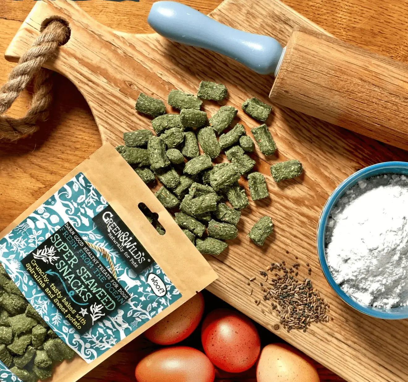 Green vegan dog treats: seaweed snacks on wooden board with blue rolling pin