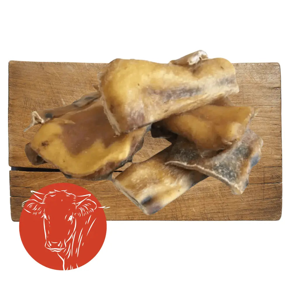 Beef muscle chew toy with goat bone on wooden board and cow logo