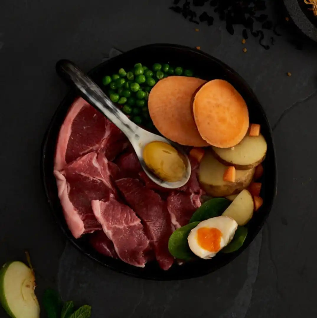 Black cast iron skillet with raw meat, vegetables and eggs.