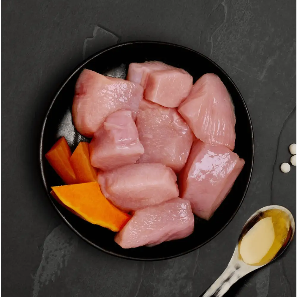 Canagan cat food can with raw chicken and pumpkin on black plate