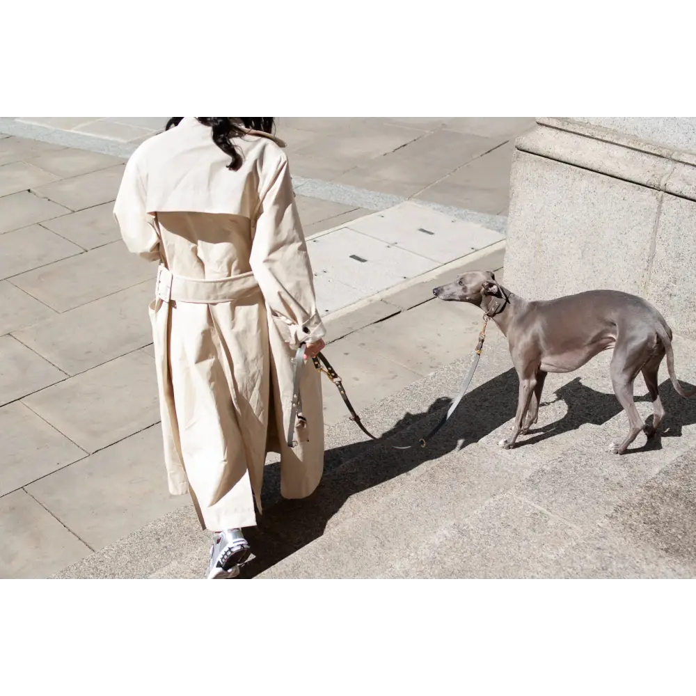 Beige trench coat with black belt and pockets featuring brass hardware and vegetable tanned leather