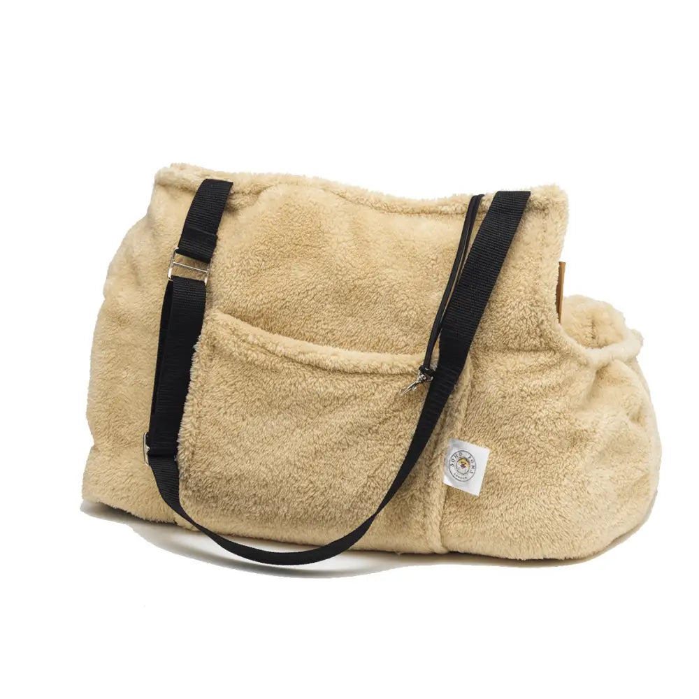 Beige fluffy duffel bag with black straps and logo, ideal for teddy bear dog carrier