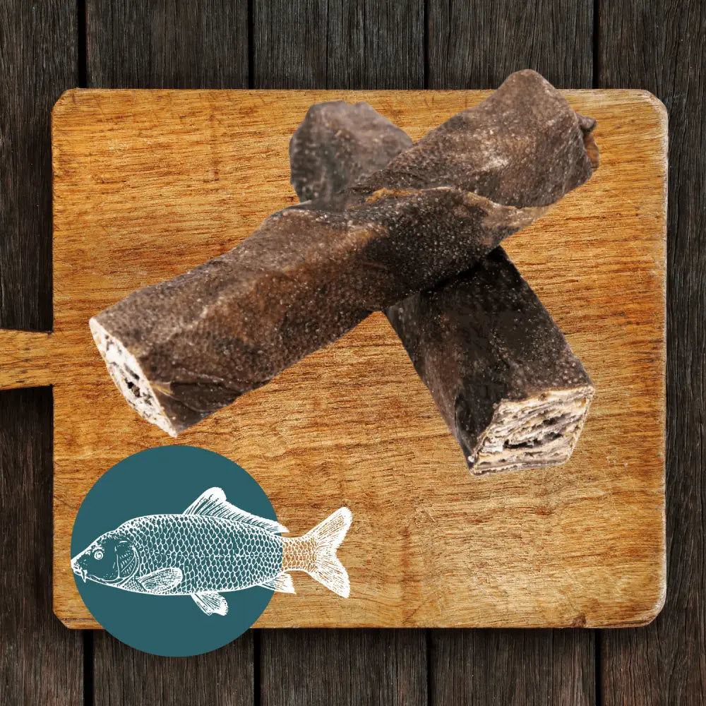 Brown fish-shaped dog treat on wooden board with teal fish icon for The Fish Chew Box wolf fish stick