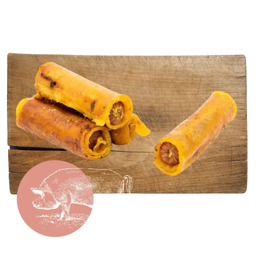 Yellow rolled dog treats on wooden surface.