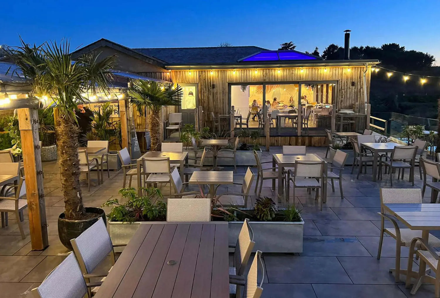 Dog-friendly patio at Apple Tree Cafe with white chairs, wooden tables, string lights