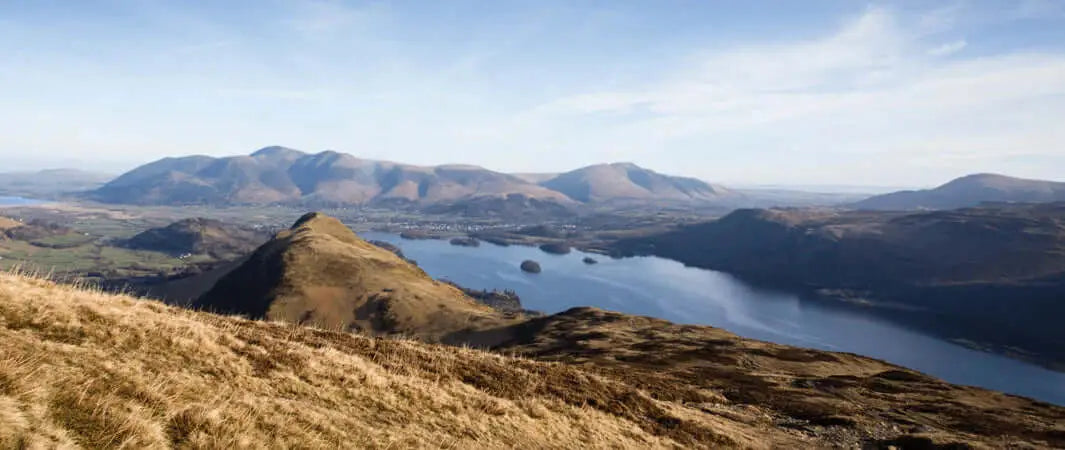 Brown grassy hillside in North West England’s Lake District with distant mountains and lake