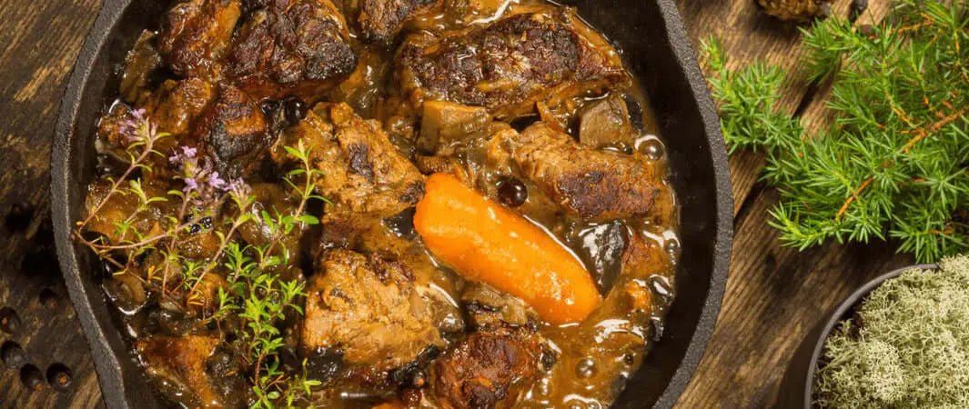 Cast iron pot of venison beef stew with carrots for furry friends