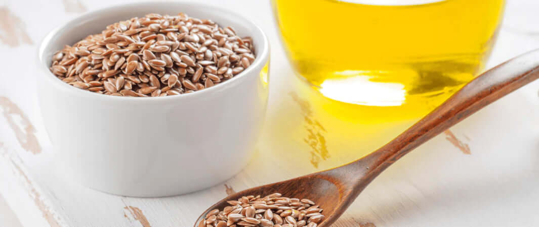 Golden flax seeds in white bowl with spoon for fabulous flaxseed oil