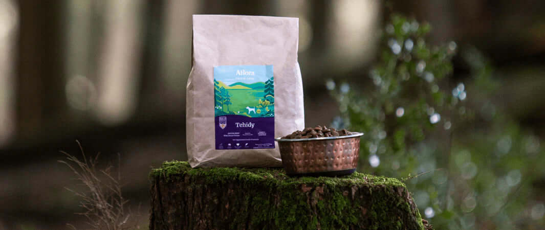 White vegetarian dog treats bag on mossy stump