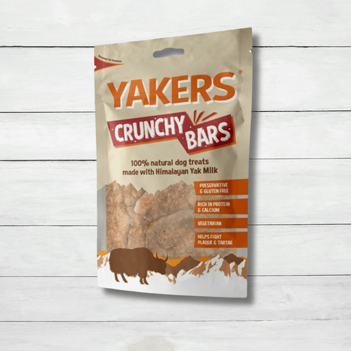 A packet of Yakers Crunchy Bars for dogs sits on a white rustic background
