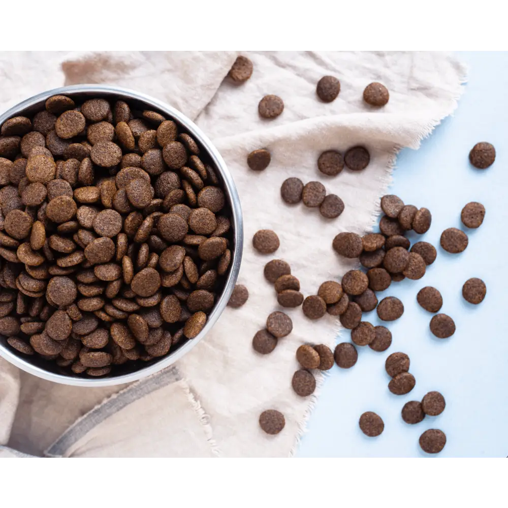 Chocolate chip cookie mix in a silver bowl with scattered chips on white cloth for grain free dog food