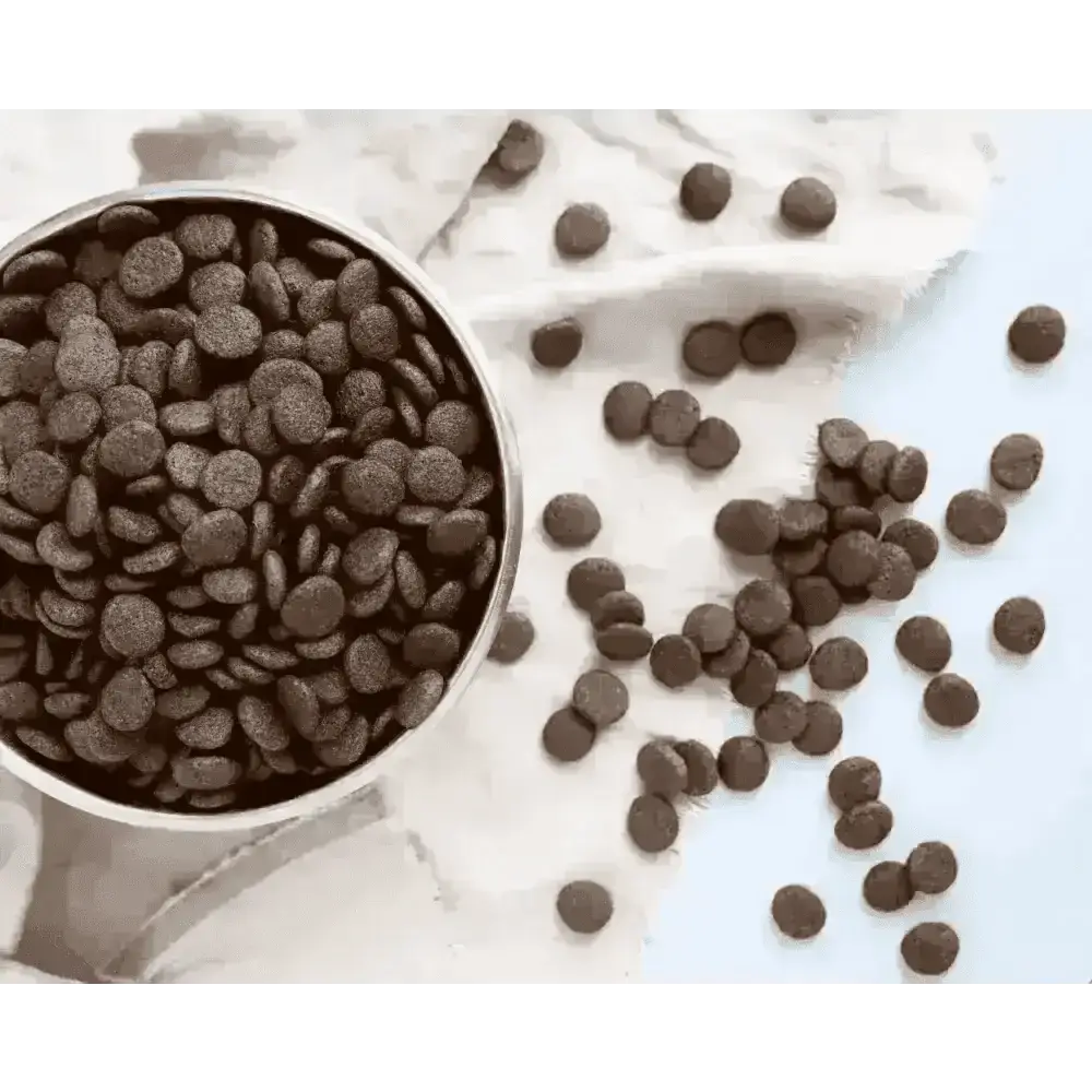 Chocolate chip cookie mix in a silver bowl with scattered chips on white cloth for grain free treats