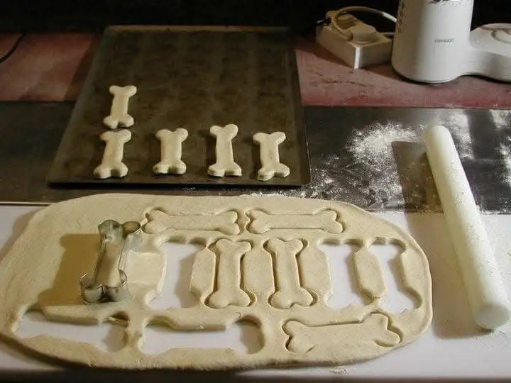 Bone-shaped cookie cutter set with white plastic handles and silver metal blades, designed for baking.