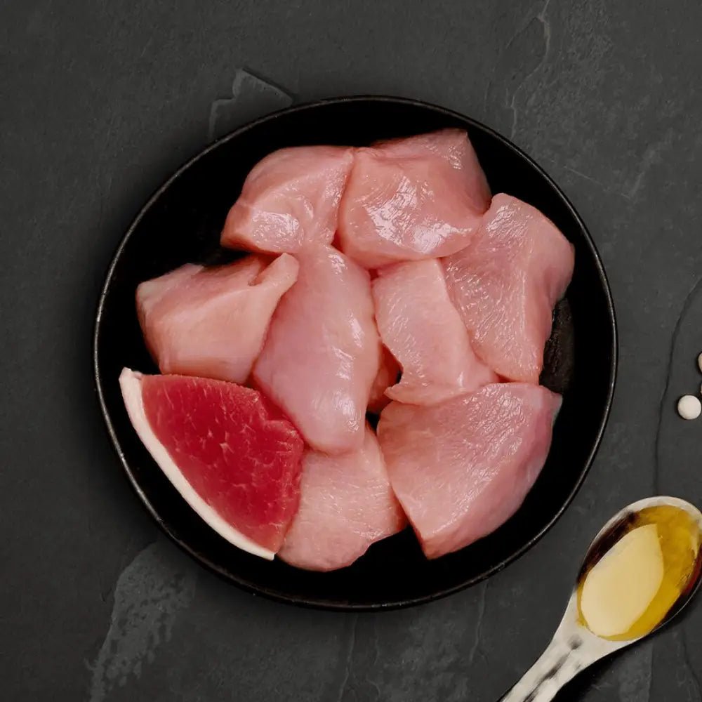 Raw chicken with ham cat food on black plate beside watermelon slice