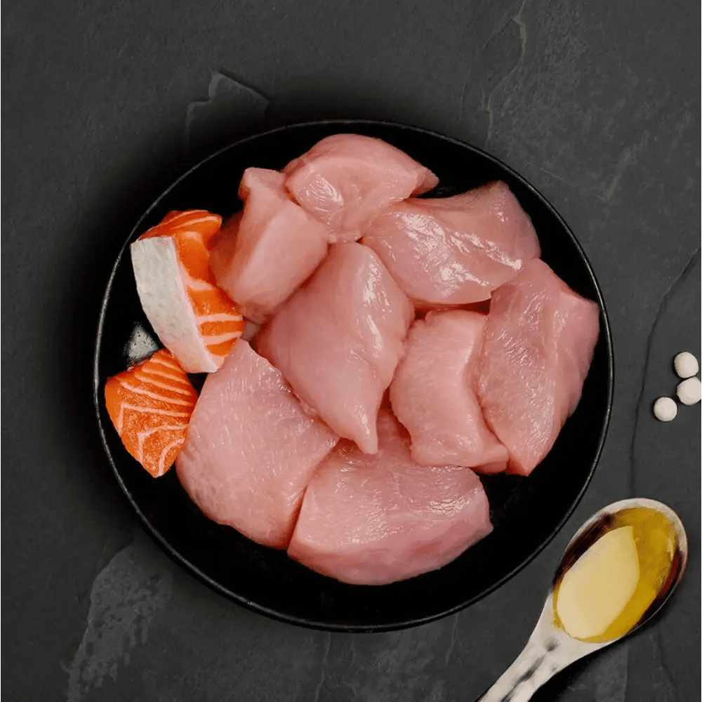 Black plate with raw chicken and salmon slices, yellow oil, for Canagan Cat Food Can