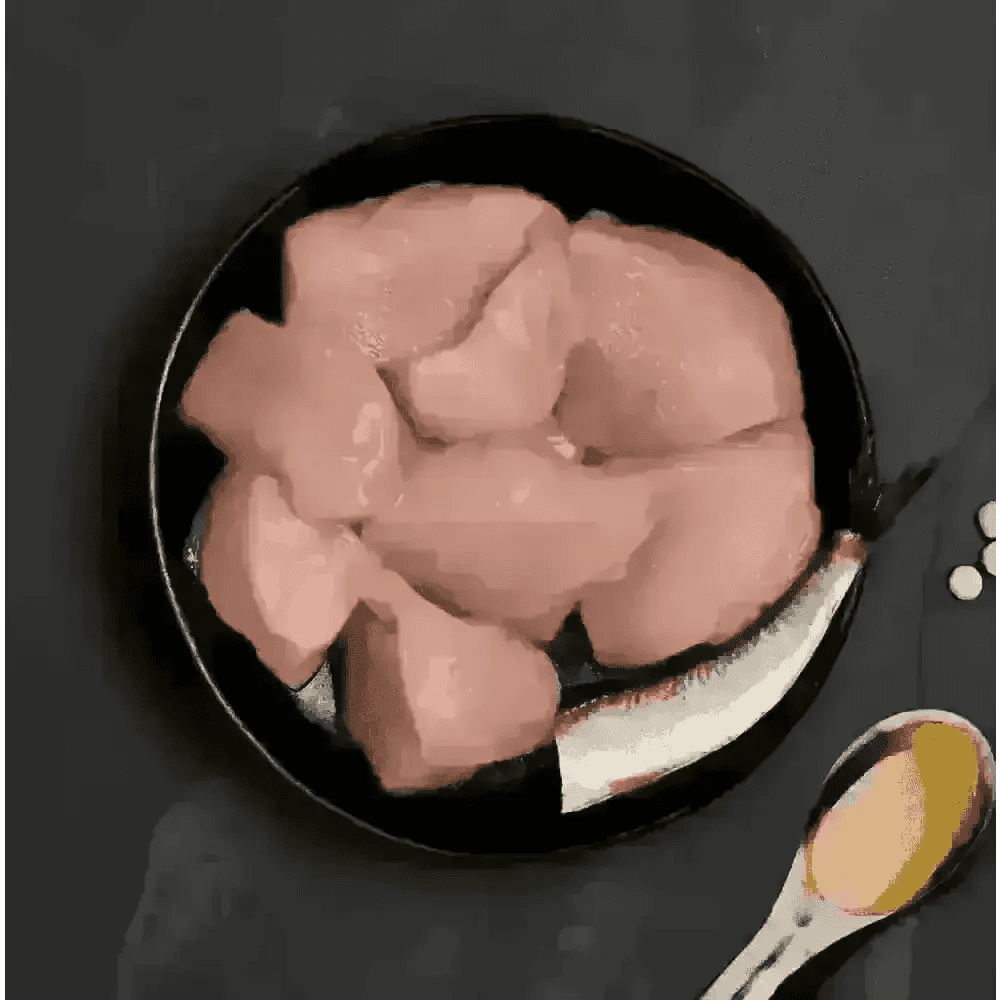 Black plate with raw chicken pieces, silver spoon, and salt shaker for Canagan Cat Food Can