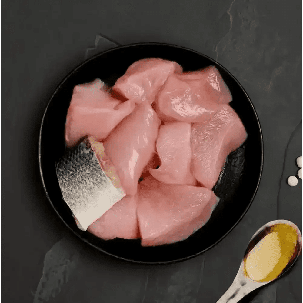 Black plate with raw fish slices and oil, ideal as highly nutritious complete cat food to accompany dry food