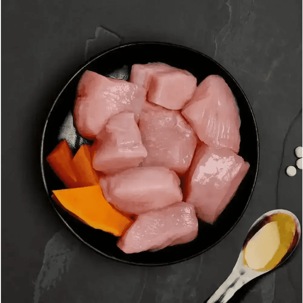 Canagan cat food can with raw chicken and pumpkin on black plate