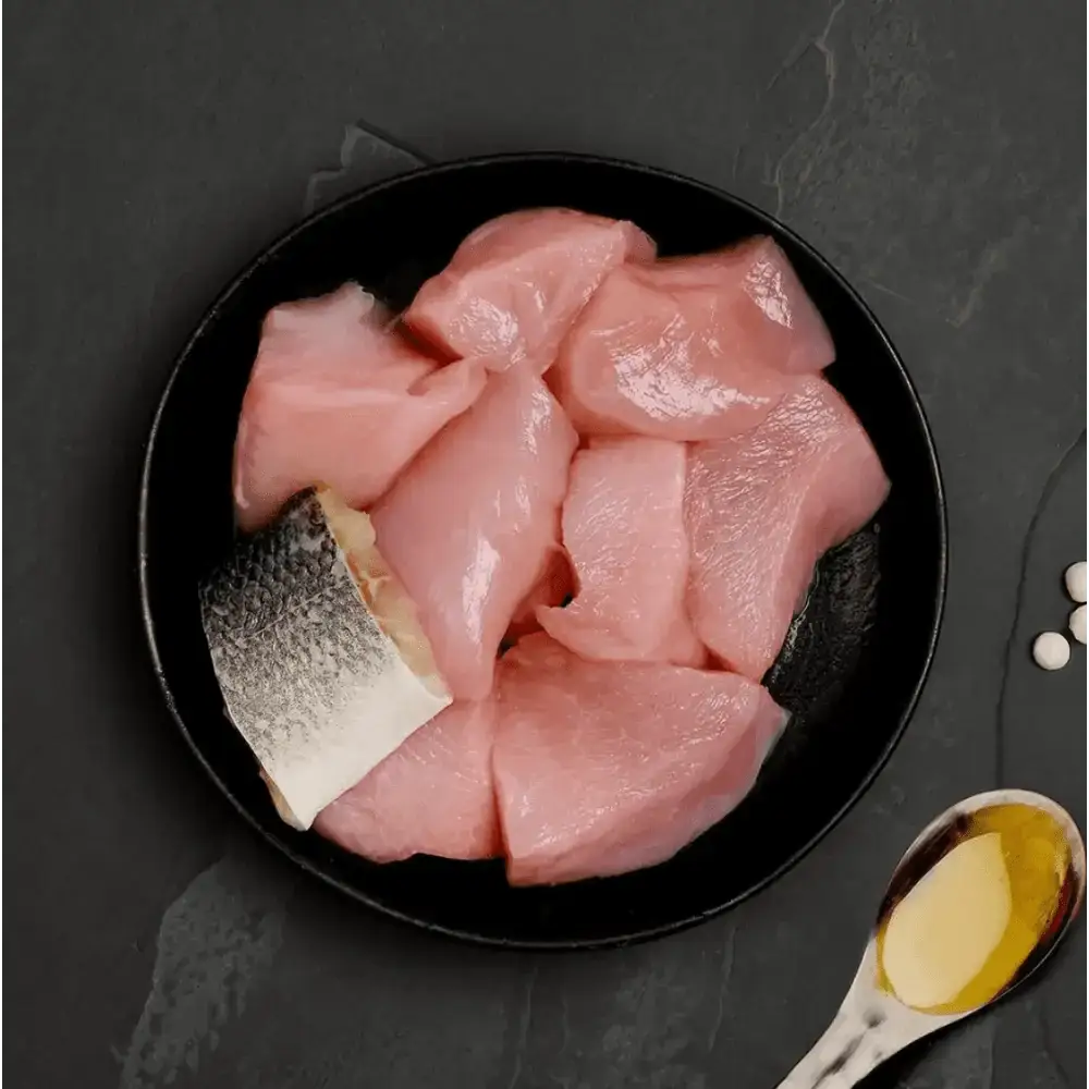 Black plate with raw fish slices and oil, ideal as highly nutritious complete cat food to accompany dry food