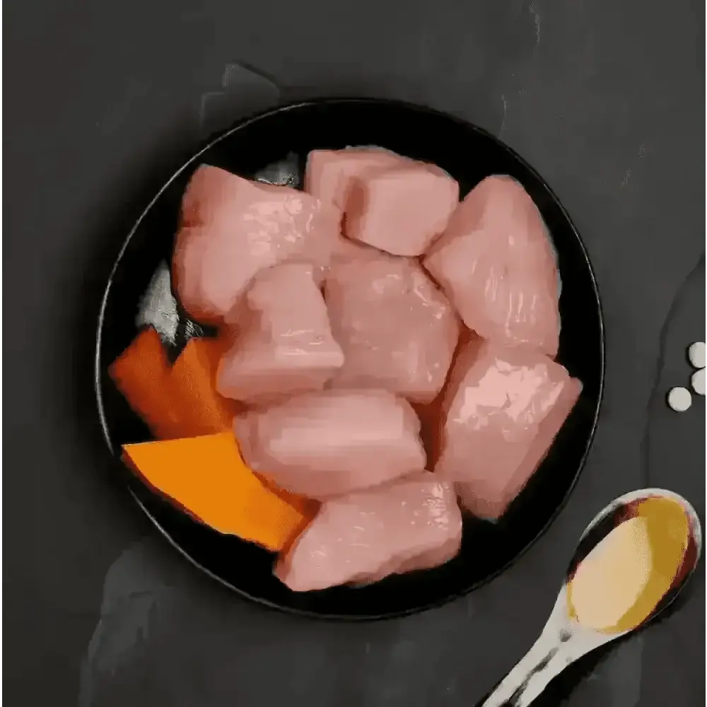 Canagan cat food can with raw chicken and pumpkin on black plate