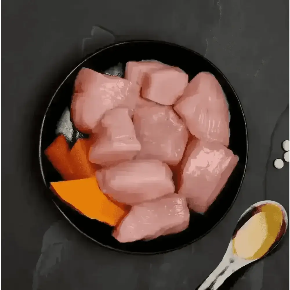 Canagan cat food can with raw chicken and pumpkin on black plate