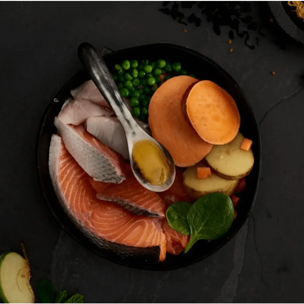 Salmon fillet with sweet potato slices and peas in a black bowl for Canagan Scottish Salmon grain free dog food