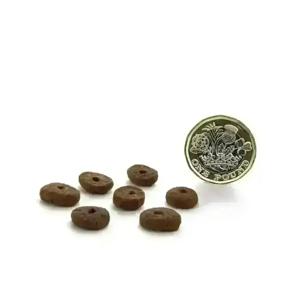 Brown small breed dog treats with holes, circular shape, textured surface, made with free-range chicken