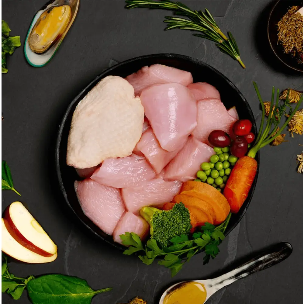 Raw chicken breast medallions with vegetables in black bowl for Canagan Wet Dog Food Senior Feast