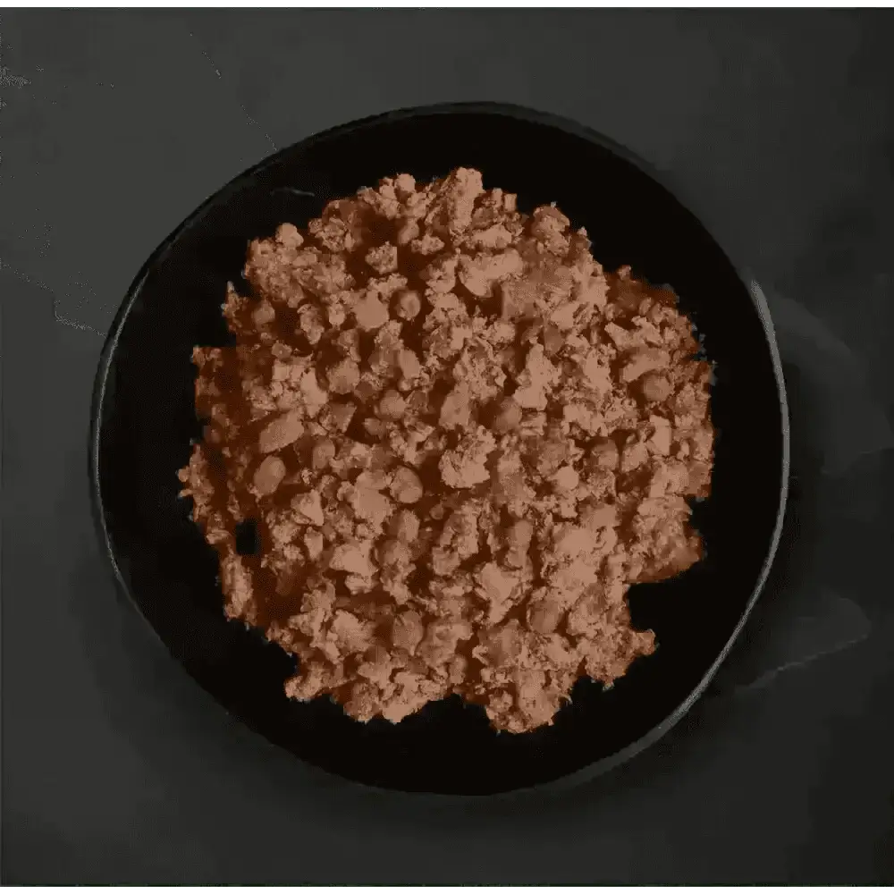 Canagan Country Game wet dog food: dark plate with ground meat, peas, carrots on black background