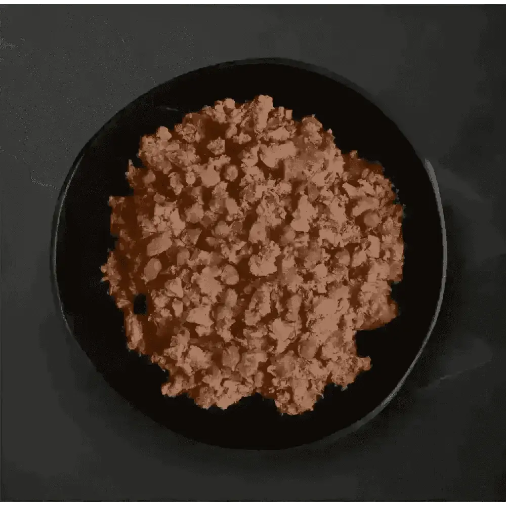 Canagan Country Game wet dog food: dark plate with ground meat, peas, carrots on black background