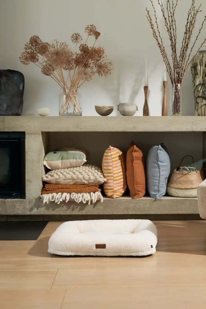 Cream-colored dog bed with brown leather tag, rectangular shape.