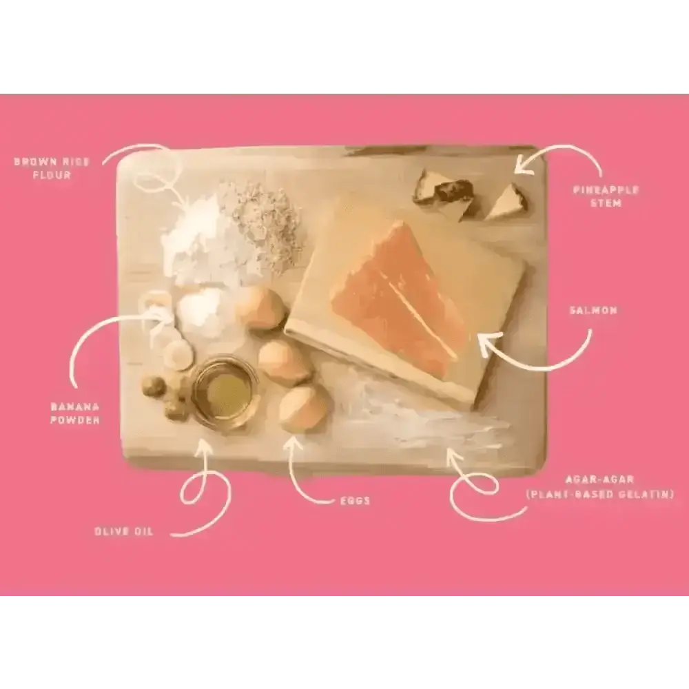 Wooden cutting board with salmon, eggs, olive oil, bananas, and pineapple slices for Earth Animal No-Hide Salmon Chew