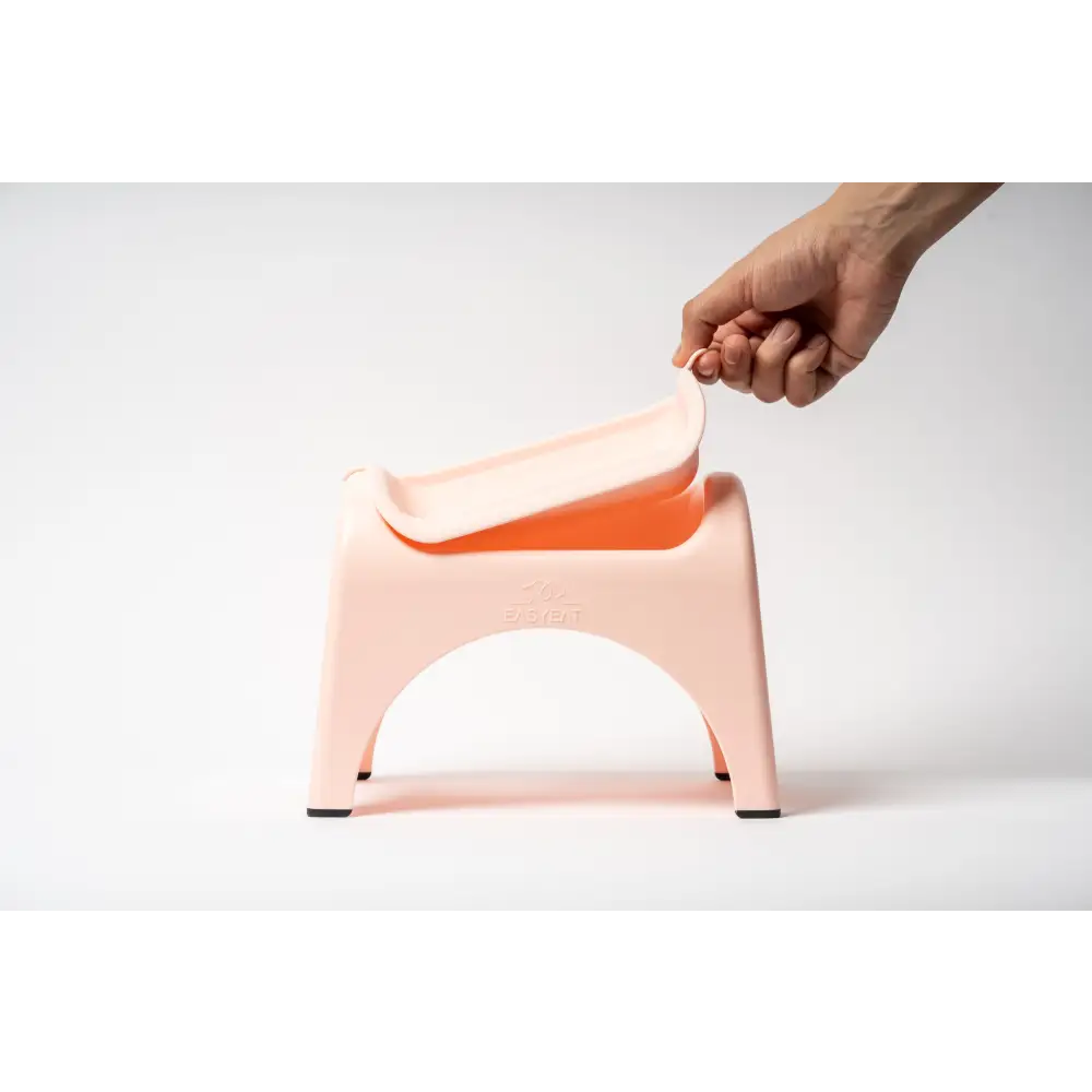 Hand lifting rose pink EasyEat 2.0 step stool with orange tray