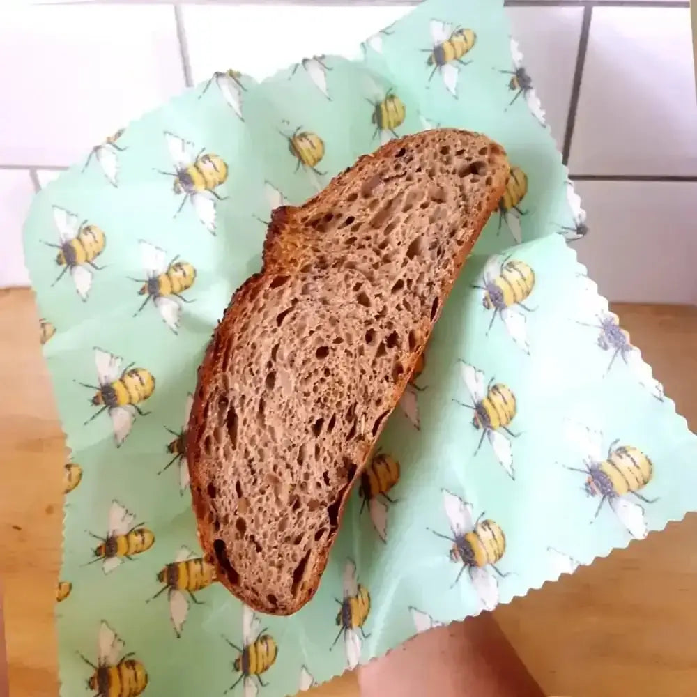 Dark brown artisan bread slice on Honey Bee Good’s eco-friendly bee-patterned wrap