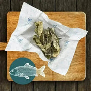 White paper with blue fish design on wooden cutting board for Fish Twirl Chew Box