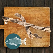 Wooden cutting board with fish design and dried seaweed pieces for Fish Twirl Chew For Dogs