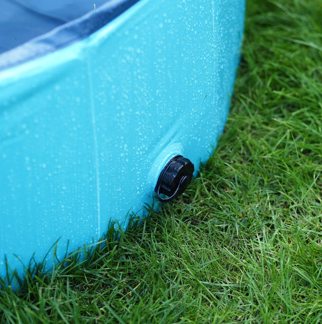 Blue plastic pet pool with a black valve on grass