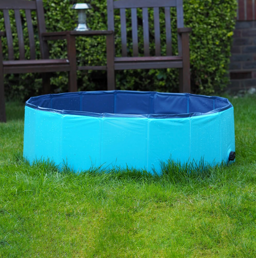 Blue inflatable pool on grass with wooden bench and garden lantern in the background