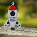 Fabric rocket-shaped dog toy with 'It's Not Rocket Science' text on a blurred natural background