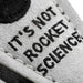 Text 'IT'S NOT ROCKET SCIENCE' on a textured surface