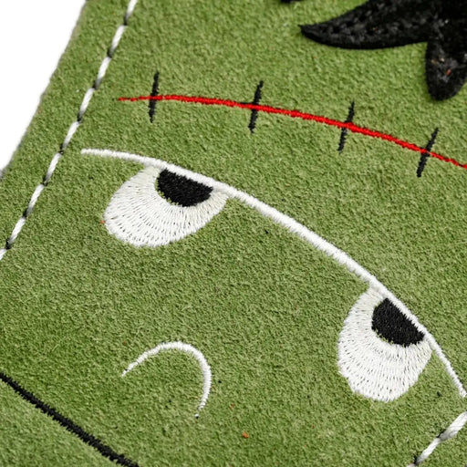 Close-up of a green fabric patch with embroidered eyes and a red line, eco friendly dog toy