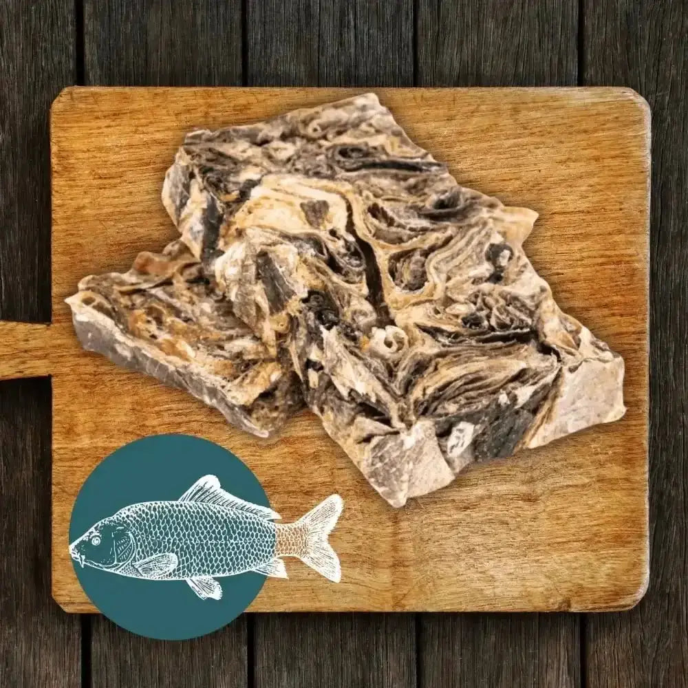 Wooden cutting board with raw mighty fish chews bones and teal fish bowl