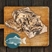 Wooden cutting board with raw mighty fish chews for dogs