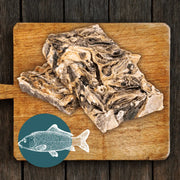 Wooden cutting board with raw mighty fish chews for dogs