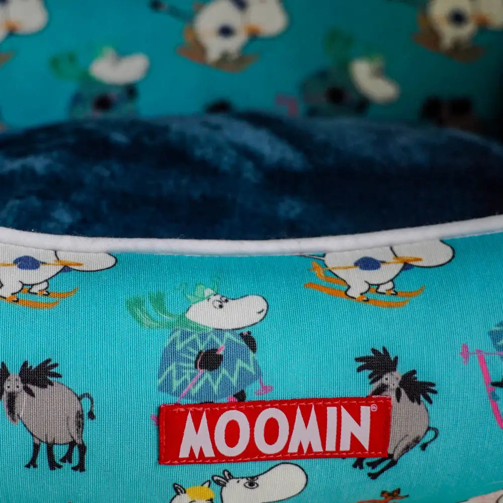 Blue Moomins plush toy with white sheep and moose on teal background for Ski Holidays Bed