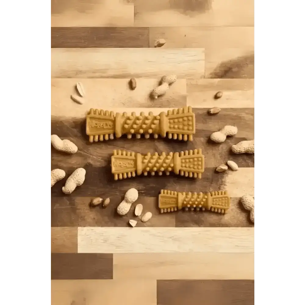 Golden textured Petello Nobblys Tough Brush peanut butter dog chew with scattered peanut shells