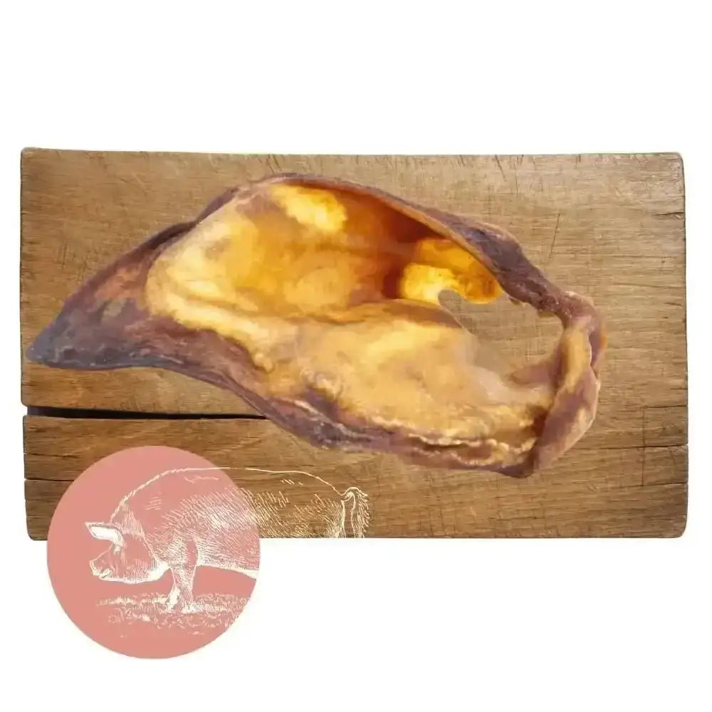 Golden pig-shaped natural dog chew from Pets Larder on wooden board