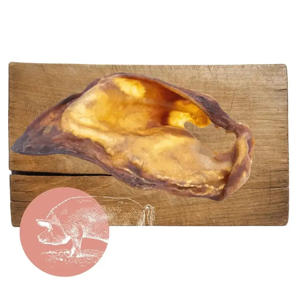 Golden pig-shaped natural dog chew from Pets Larder on wooden board